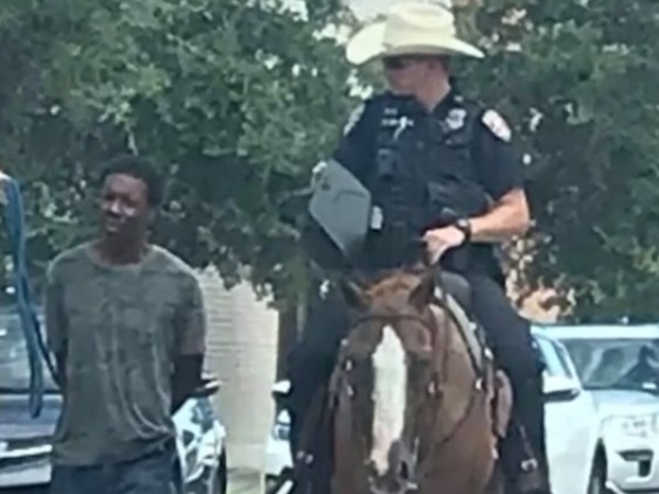 Снимки на двама бели конни полицаи, водещи чернокож мъж, вързан
