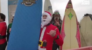 Стотици хора облечени в костюми на Дядо Коледа сърфираха по