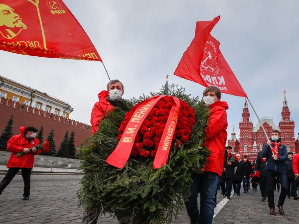 Малка група руски комунисти, носещи защитни маски и червени знамена,