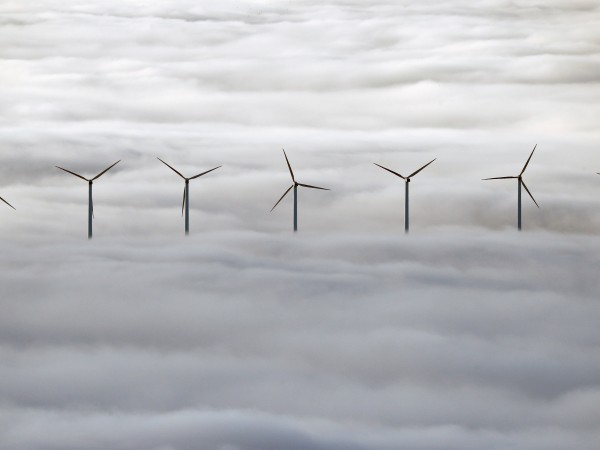 Вятърни генератори се издигат на есенната мъгла край испанския град