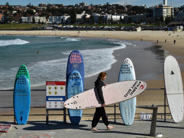 Сърфист преминава покрай плаж в Сидни, Австралия. Снимка: БГНЕСПо публикацията